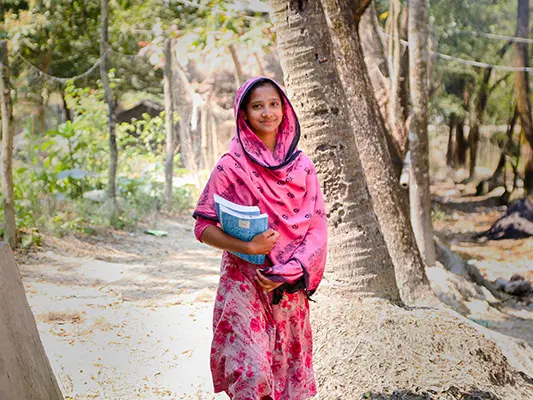 Marzia, 17, carrying books home from a new learning centre in Bangladesh.